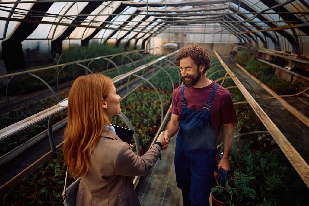 Farming Friend team member shaking hands with a farmer in a greenhouse
